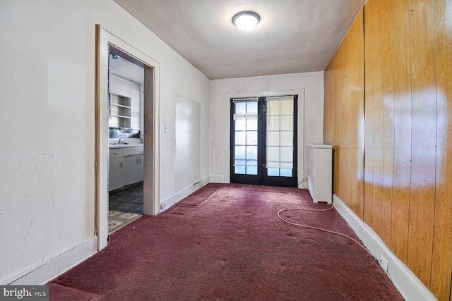 doorway to outside featuring carpet floors, french doors, wood walls, and baseboards