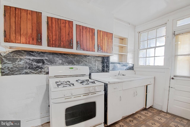 kitchen featuring gas range gas stove, light floors, open shelves, light countertops, and a sink