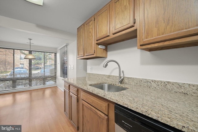 kitchen featuring decorative light fixtures, a sink, light stone countertops, light wood-type flooring, and dishwashing machine