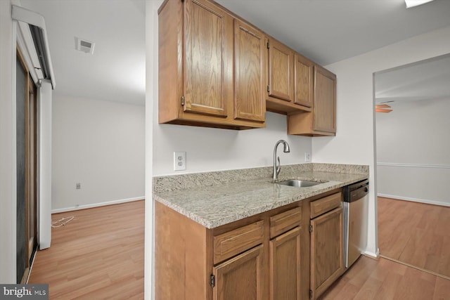 kitchen featuring baseboards, visible vents, a sink, light wood-style floors, and stainless steel dishwasher