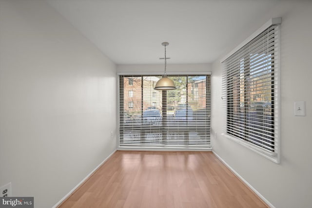 unfurnished dining area with wood finished floors and baseboards