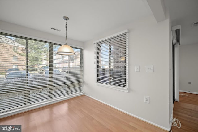 unfurnished dining area with baseboards, visible vents, and light wood finished floors