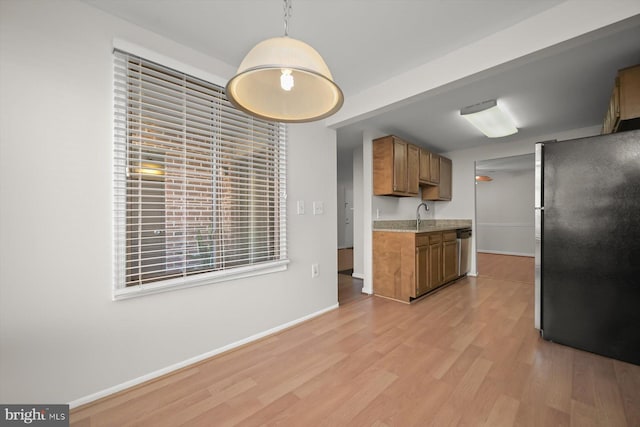 kitchen featuring baseboards, appliances with stainless steel finishes, light wood-type flooring, brown cabinets, and decorative light fixtures