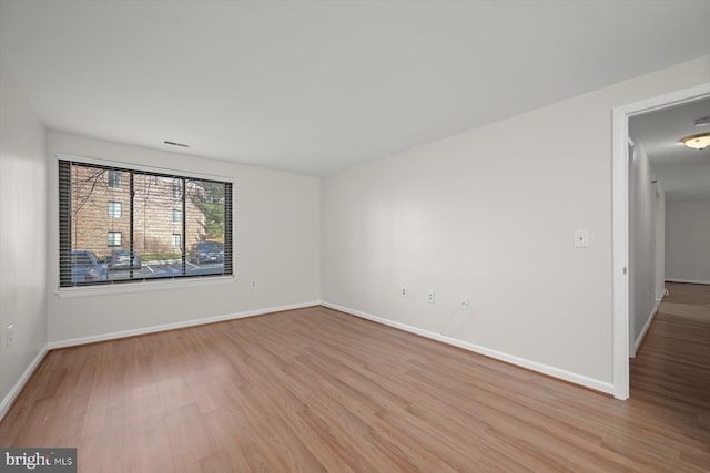 unfurnished room with visible vents, light wood-style flooring, and baseboards