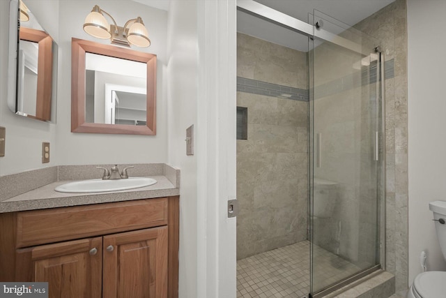 full bath featuring toilet, a stall shower, and vanity