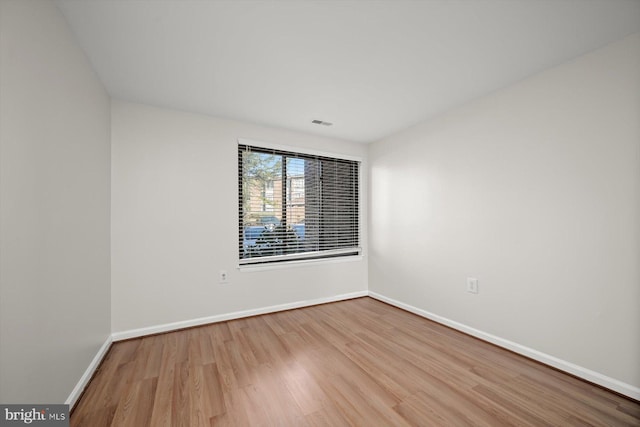 unfurnished room featuring visible vents, baseboards, and wood finished floors