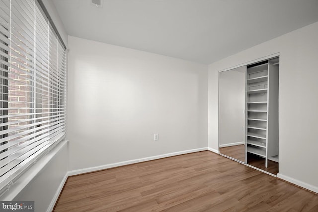 unfurnished bedroom featuring a closet, wood finished floors, visible vents, and baseboards