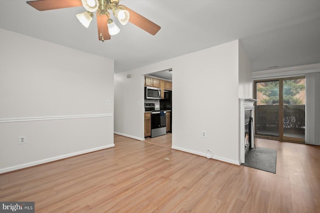 unfurnished living room featuring baseboards, ceiling fan, a fireplace, and light wood-style floors