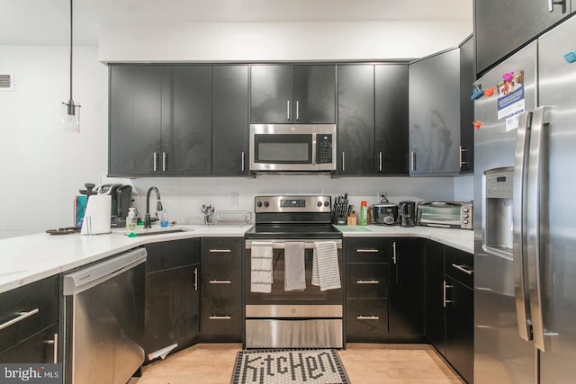 kitchen featuring a toaster, decorative backsplash, appliances with stainless steel finishes, dark cabinets, and a sink