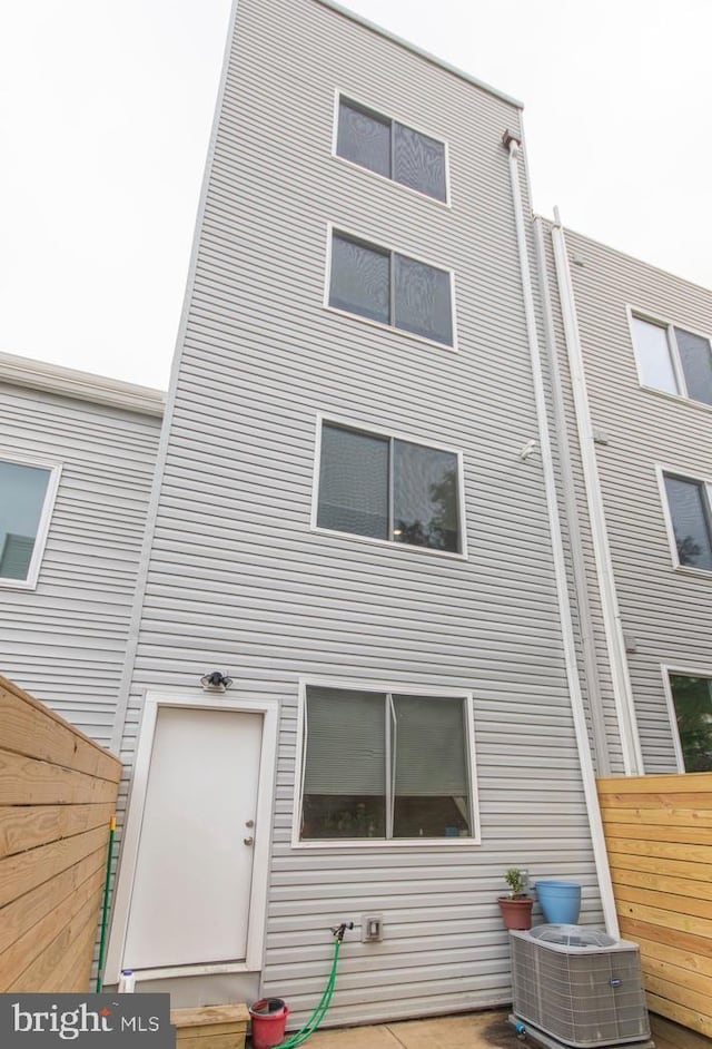 rear view of property featuring central air condition unit and fence