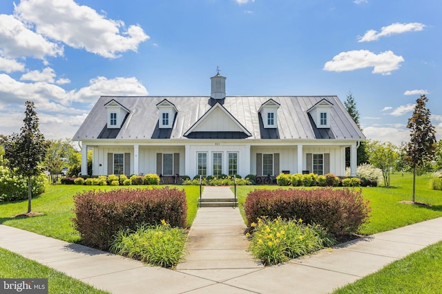 cape cod home featuring board and batten siding, a front yard, and a standing seam roof