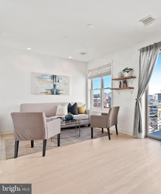 living area with baseboards, visible vents, and light wood-style floors