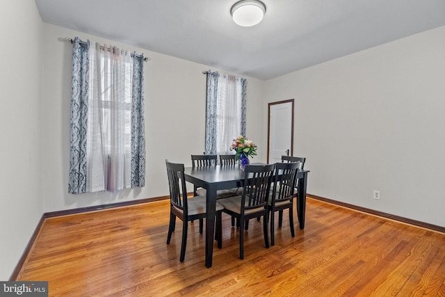 dining space with light wood-style flooring and baseboards