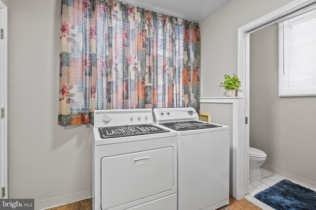 washroom with laundry area, light tile patterned floors, baseboards, and separate washer and dryer