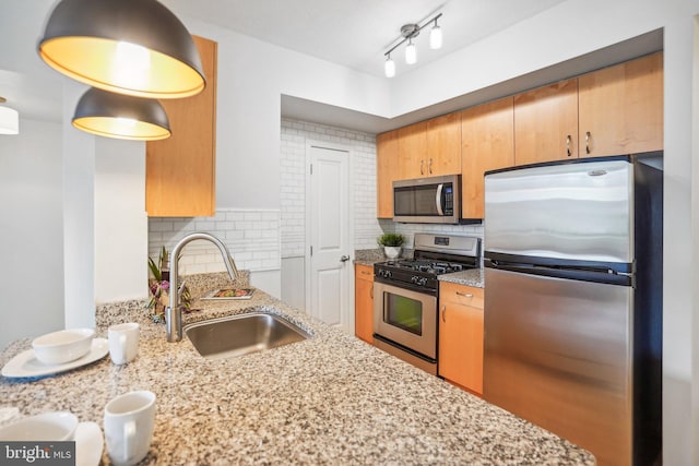 kitchen featuring light stone countertops, backsplash, stainless steel appliances, and a sink