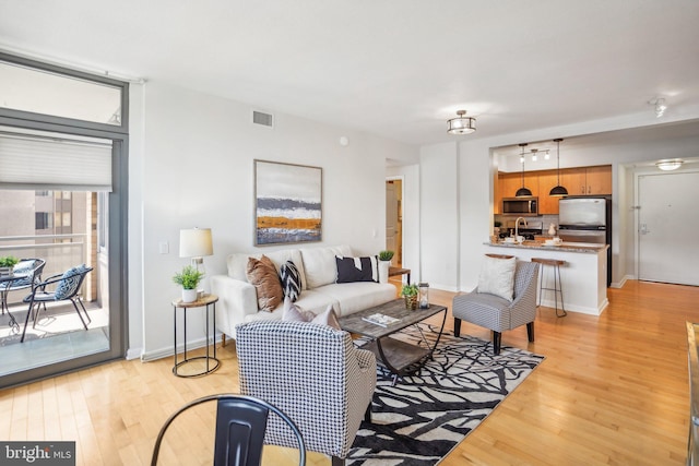 living area with light wood finished floors, baseboards, and visible vents