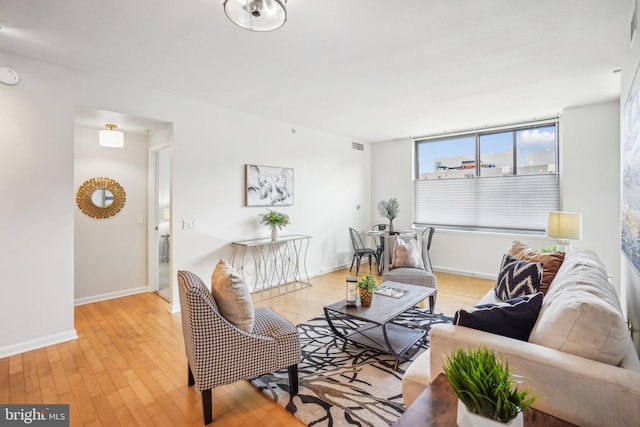 living room with baseboards, visible vents, and light wood-style floors