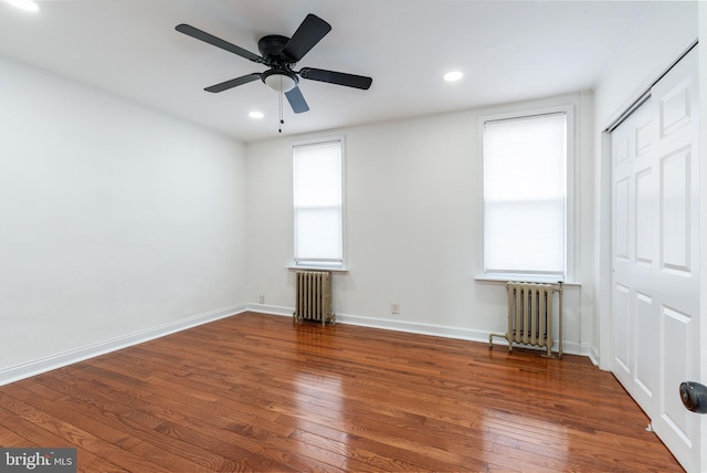 unfurnished bedroom with radiator heating unit, recessed lighting, hardwood / wood-style flooring, and baseboards