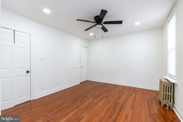 spare room featuring recessed lighting, wood-type flooring, radiator heating unit, ceiling fan, and baseboards