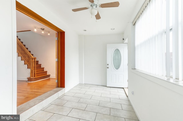 foyer featuring a ceiling fan, stairway, baseboards, and tile patterned floors