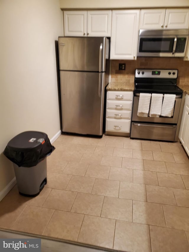 kitchen with light stone counters, white cabinetry, appliances with stainless steel finishes, light tile patterned flooring, and baseboards