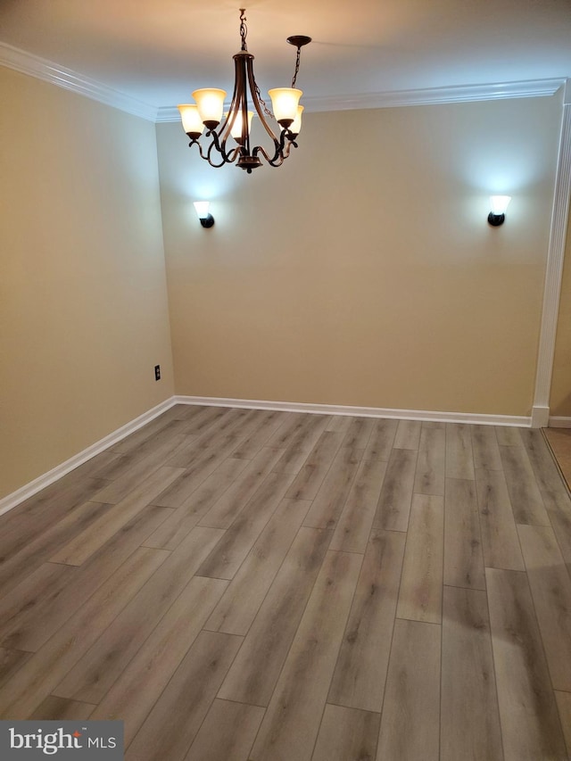 unfurnished dining area with an inviting chandelier, crown molding, wood finished floors, and baseboards