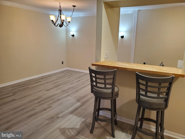 interior space with wood finished floors, baseboards, a chandelier, and ornamental molding