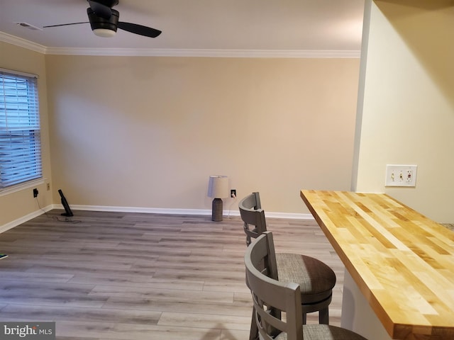 interior space with visible vents, crown molding, baseboards, wood finished floors, and a ceiling fan