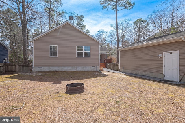 view of home's exterior featuring crawl space, a fire pit, and fence