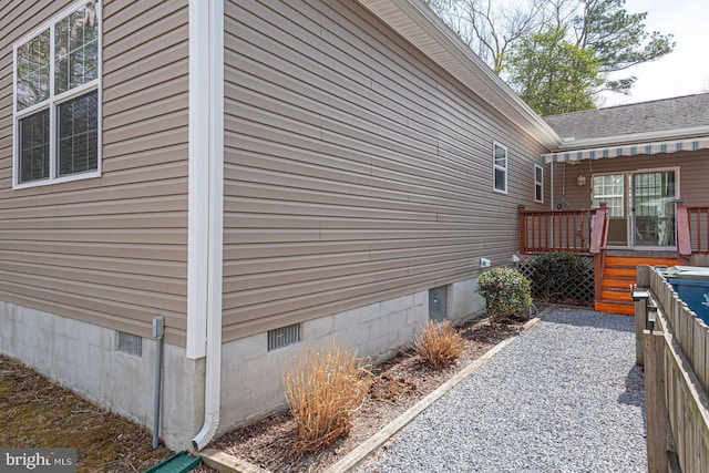 view of side of home featuring crawl space, a wooden deck, and a shingled roof