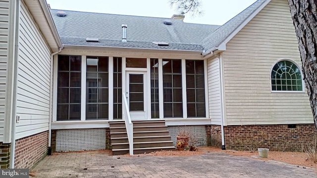 view of property exterior featuring entry steps, a patio, a shingled roof, a sunroom, and crawl space