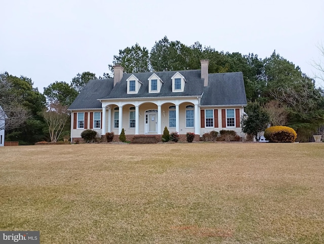 cape cod-style house featuring a porch, a chimney, and a front lawn