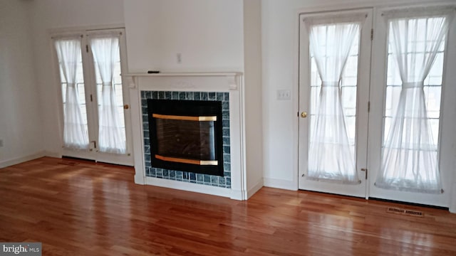 entryway featuring baseboards, visible vents, a tiled fireplace, and wood finished floors