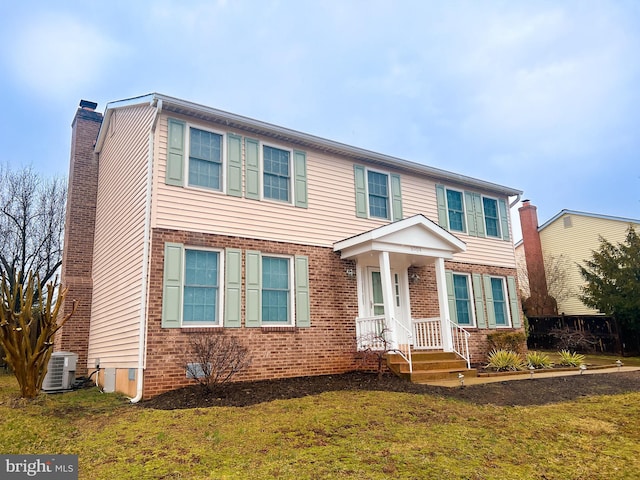 view of front of house featuring a chimney, central AC unit, a front lawn, and brick siding