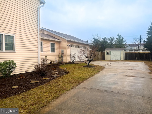 exterior space with a garage, driveway, a shed, and fence