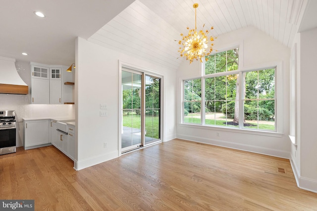 unfurnished dining area with light wood finished floors, baseboards, a chandelier, vaulted ceiling, and recessed lighting