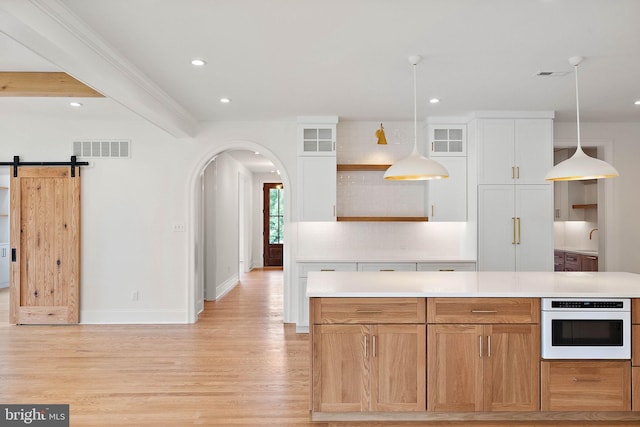 kitchen with white oven, light wood-type flooring, visible vents, and light countertops