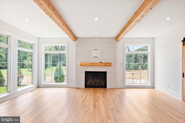 unfurnished living room featuring beam ceiling, a brick fireplace, baseboards, and wood finished floors