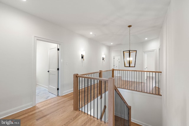 hallway with wood finished floors, recessed lighting, an upstairs landing, and baseboards