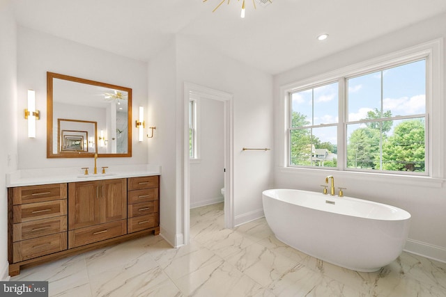 bathroom with a freestanding tub, marble finish floor, recessed lighting, baseboards, and vanity