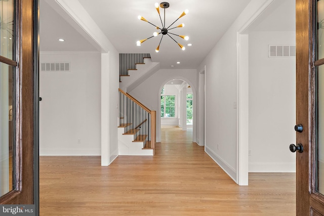 entrance foyer with light wood-type flooring, visible vents, a notable chandelier, stairway, and baseboards