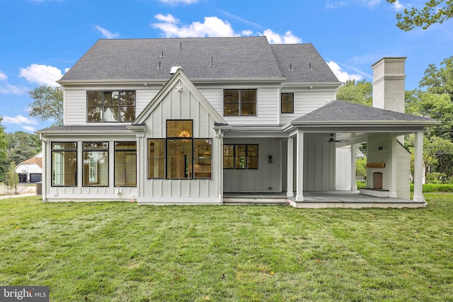 back of property with board and batten siding, a shingled roof, a lawn, a patio area, and a ceiling fan