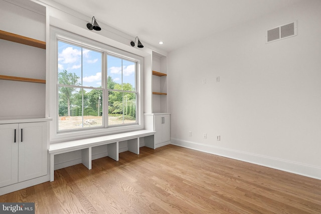 interior space with light wood finished floors, visible vents, baseboards, built in features, and recessed lighting