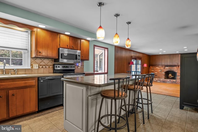 kitchen featuring stainless steel appliances, a breakfast bar, a fireplace, a sink, and tasteful backsplash