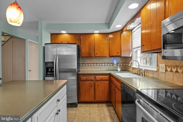 kitchen with stainless steel appliances, brown cabinetry, a sink, and decorative backsplash