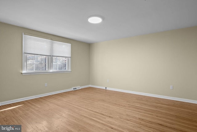 unfurnished room featuring light wood-type flooring, visible vents, and baseboards