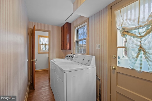 laundry area with cabinet space, washing machine and dryer, wood finished floors, baseboards, and wallpapered walls