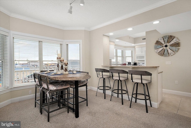 dining area with light tile patterned floors, baseboards, a textured ceiling, and ornamental molding