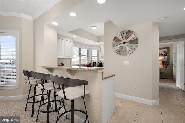 kitchen featuring a breakfast bar, white cabinetry, baseboards, and light tile patterned floors