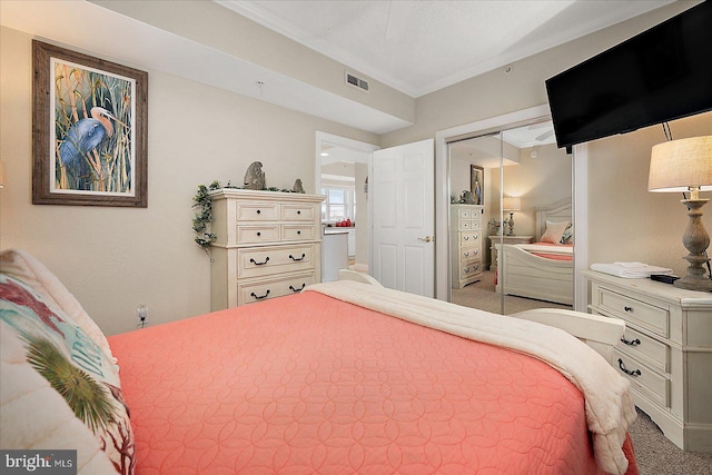 carpeted bedroom with a closet, visible vents, and crown molding